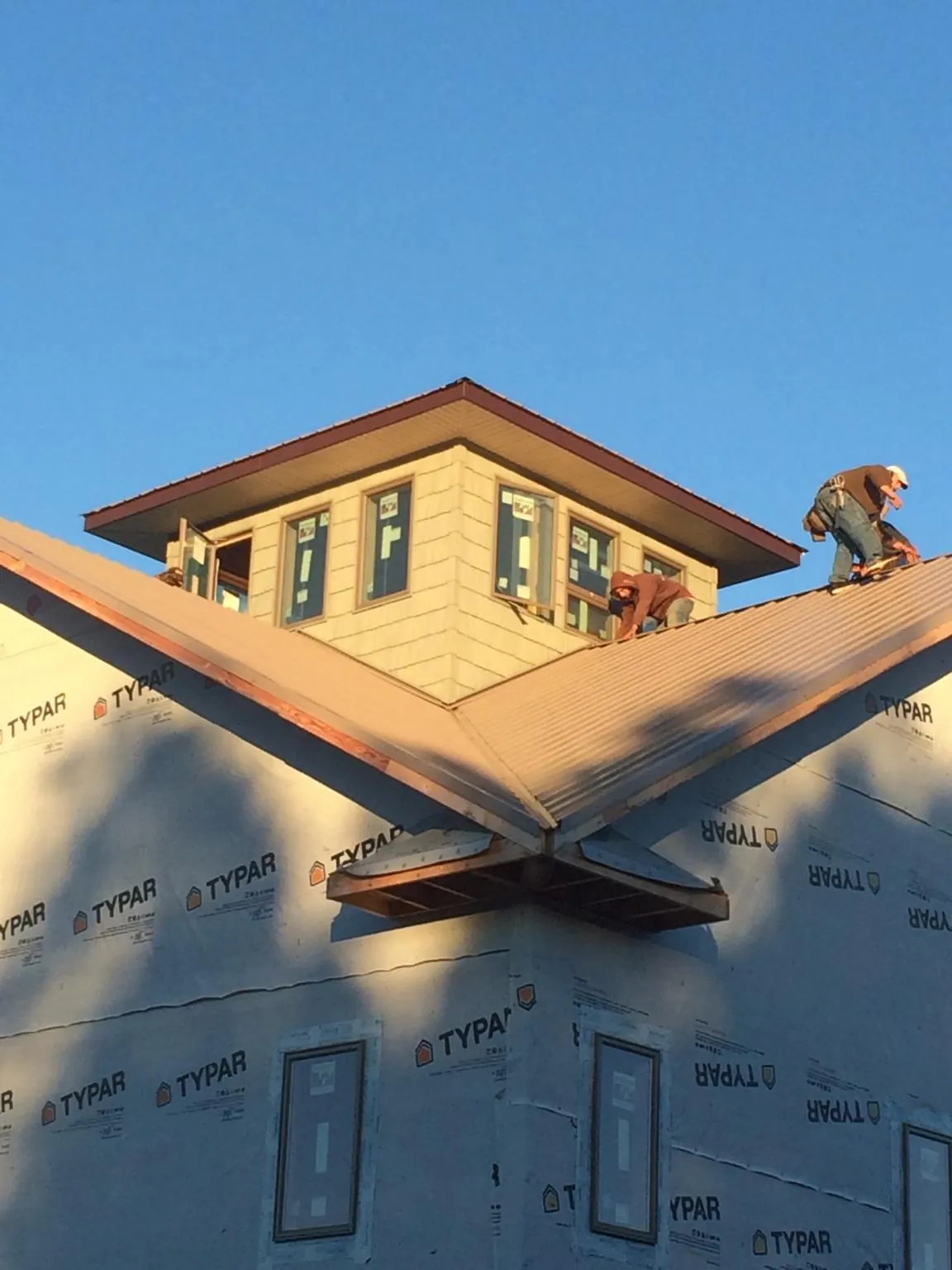 Roofers working around a rooftop cupola on a new metal roof at sunset — Roof Waterproofing in Hollandale by Roofing Brothers